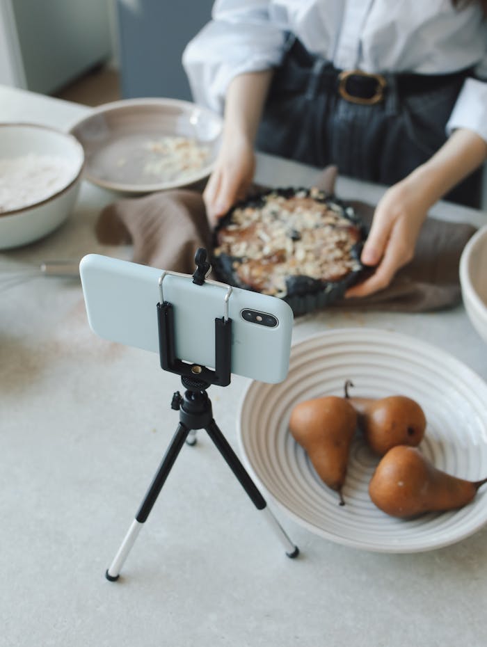 Woman records pie baking process on smartphone, highlighting food preparation and vlogging.